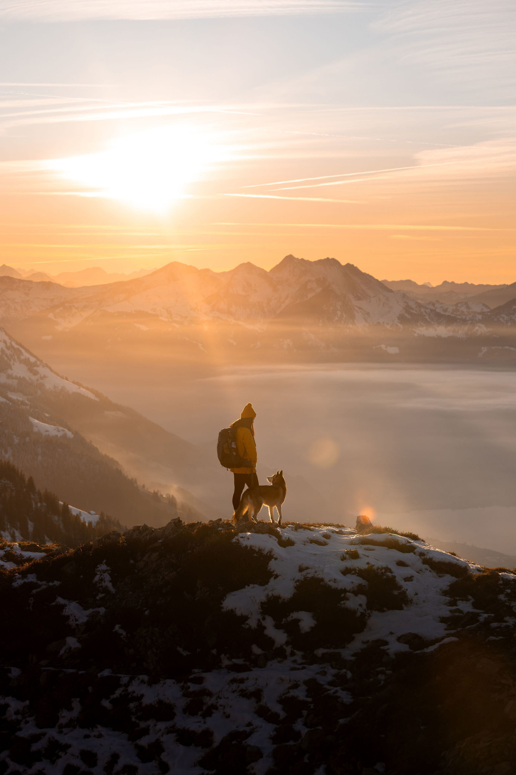 Sunset over a Swiss valley. A girl and her dog in front of mighty mountains
